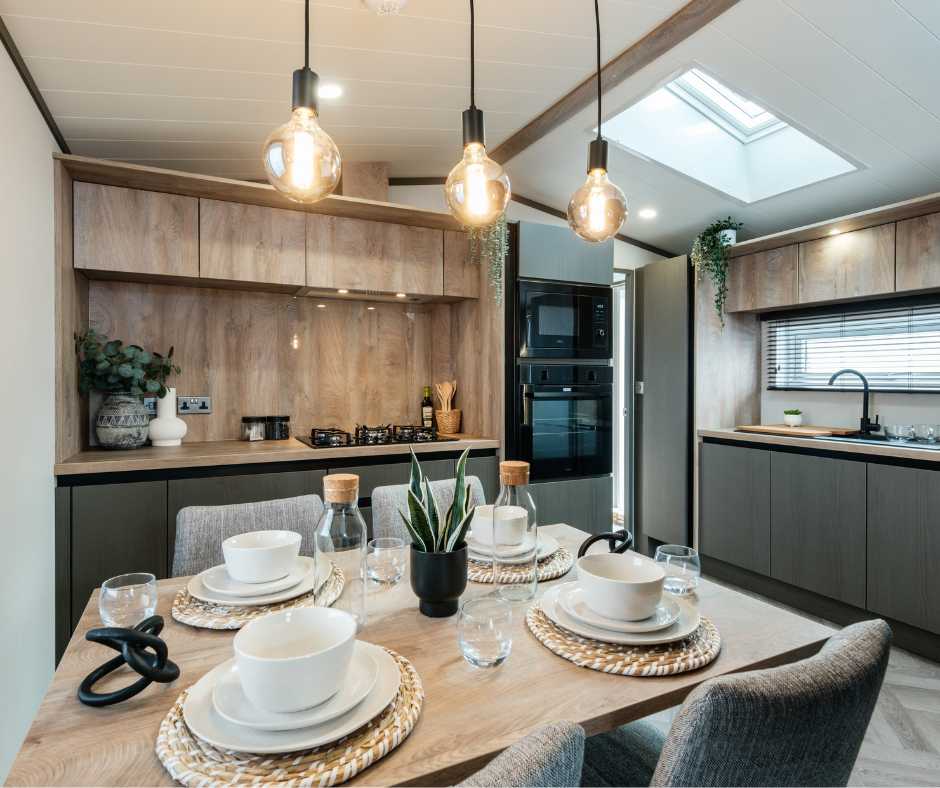 Modern open-plan kitchen and dining area with wooden cabinets, pendant lighting, and a fully set dining table